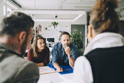 Confident male and female entrepreneurs at table during meeting in creative office