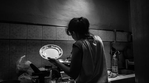 Side view of woman cooking food in kitchen at home