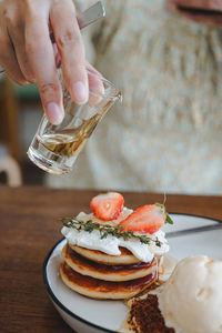 Cropped hand of person pouring drink on table