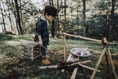 Full length of boy cooking sweet potato in forest