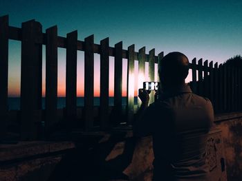 Rear view of man taking picture of a mobile phone