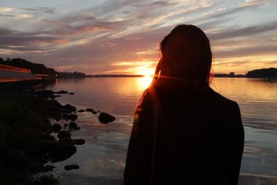 Silhouette man looking at sea against sky during sunset