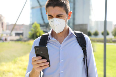 Man using mobile phone against buildings