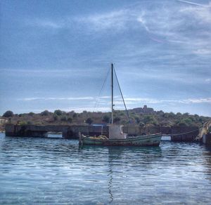 Sailboats moored on lake against sky