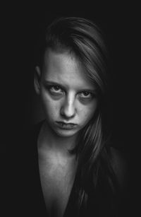 Close-up of angry young woman against black background