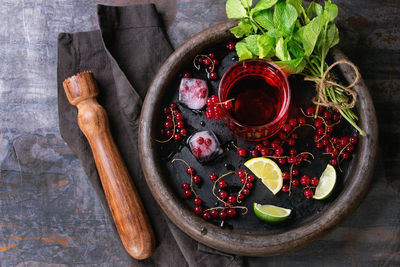 High angle view of red currants with juice and herbs on table