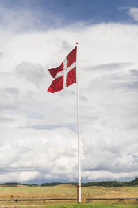 Danish flag on a flagpole against a beautiful cloudy sky