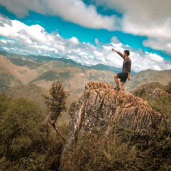 Full length of man standing on rock against sky