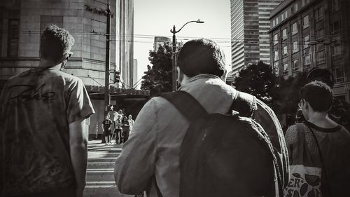 Rear view of people walking on street against buildings