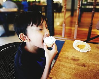 Close-up of boy eating cupcake in restaurant