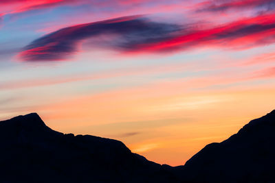 Scenic view of silhouette mountains against orange sky