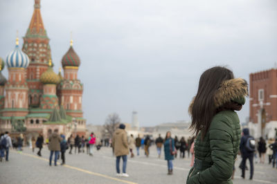 Side view of woman in jacket standing against st basil cathedral