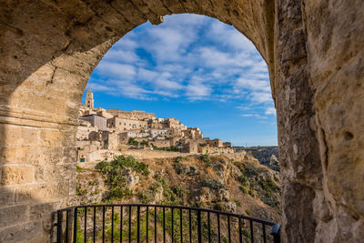 Low angle view of buildings seen through arch at sassi di matera
