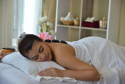 Midsection of woman lying on bed at home