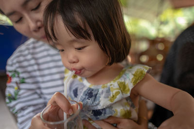 Midsection of woman feeding daughter water in glass 