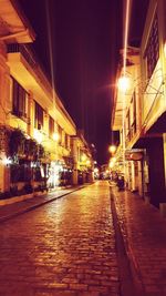 Illuminated street amidst buildings at night