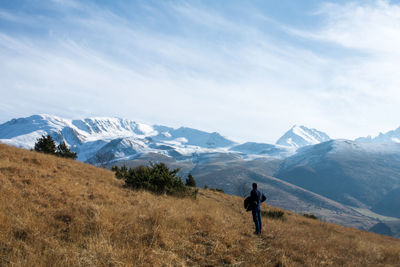 Rear view of man on snowcapped mountains against sky