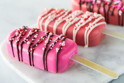 A close up of homemade cakesicles for valentine's day on a marble slab.