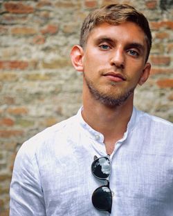 Portrait of young man standing against brick wall