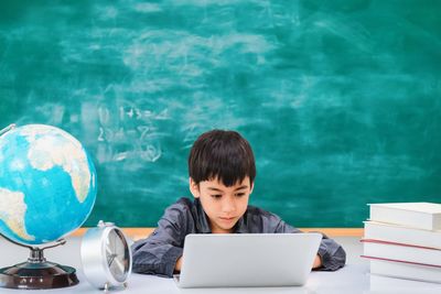 Side view of boy using mobile phone on table