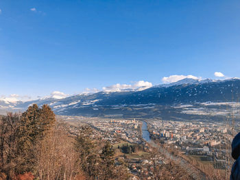 Aerial view of townscape and mountains against blue sky