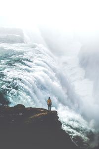 Man standing on rock against sky