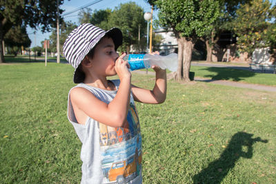 Full length of boy drinking water in park