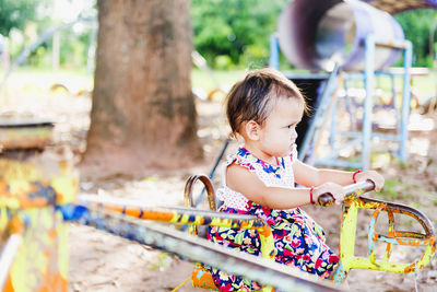 A picture of an asian child playing on the outdoor carousel alone.