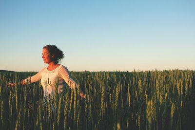 Woman standing at farm against clear blue sky during sunset