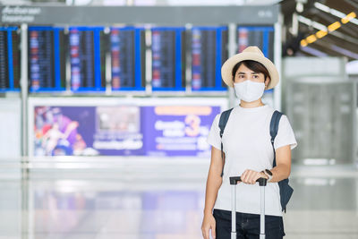 Woman wearing mask looking away while standing at airport