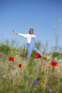 Rear view of woman standing on field against sky