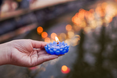 Close-up of hand holding illuminated candles