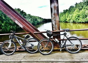 Bicycle parked by river against sky