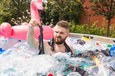 Portrait of young man holding swimming pool