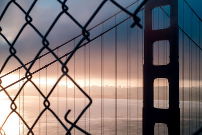 Chainlink fence against sky during sunset