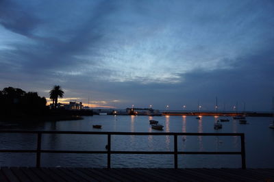 Boats in calm sea against cloudy sky