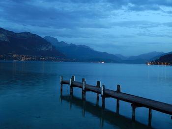 Pier on lake by town against sky