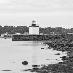 View of lighthouse by building against sky