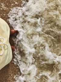 High angle view of person hand in water