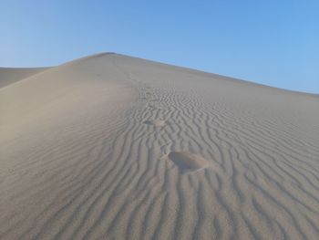 Sand dunes in desert against clear blue sky