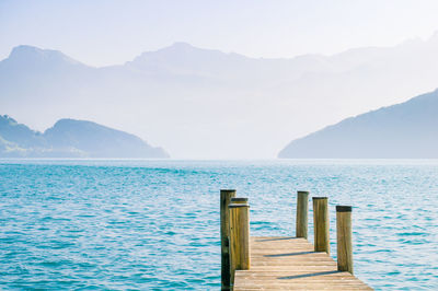 Wooden posts in sea against sky