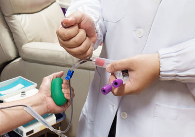 Doctor collecting samples while man donating blood in hospital