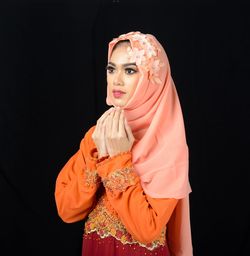 Midsection of woman standing against black background