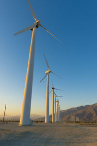 Windmill on field against clear blue sky