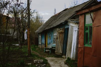 Old house by building against sky