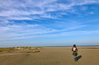 Rear view of woman on beach against sky