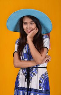 Portrait of a smiling young woman against yellow background