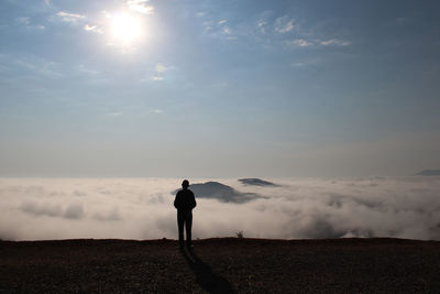 Man standing on field against sky during sunset