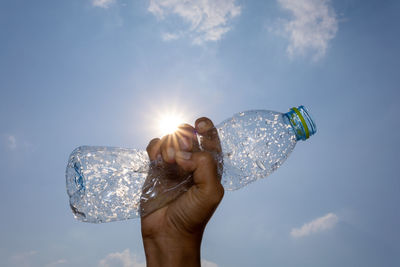 Midsection of person holding sun against sky