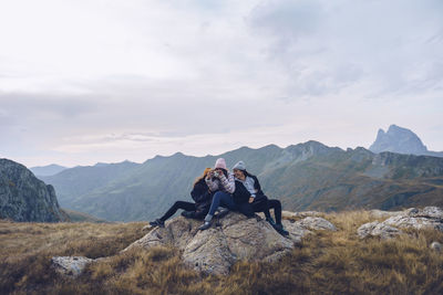 People sitting on mountain against sky